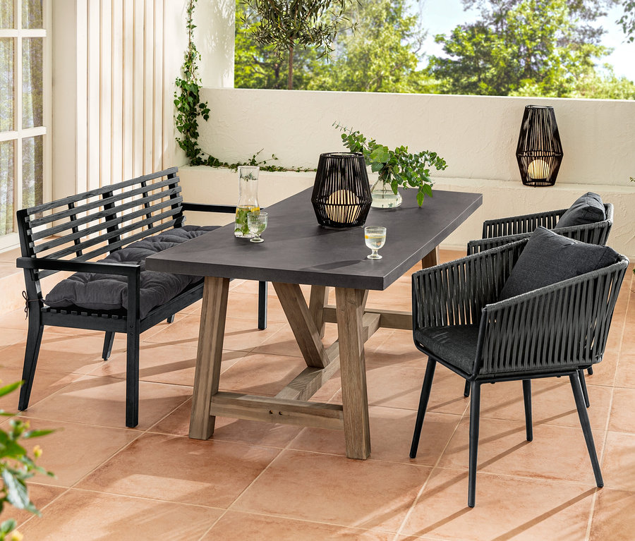 Kolçaklı Bahçe Bankı, Sun Garden bahçe bankı minderi, yemek masası, kumaş örgülü yemek sandalyeleri ve tekstil bantlı güneş enerjili fener içeren bir bahçe oturma grubu.